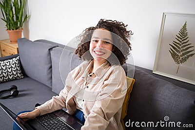 Mixed rase girl is sitting on couch and looking at camera. Stock Photo