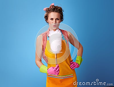 Happy modern housewife blowing on duster brush on blue Stock Photo