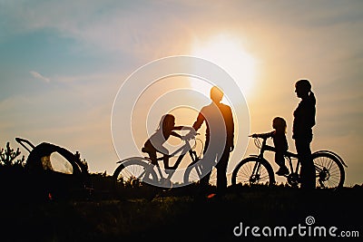 Happy mom, dad with kids biking at sunset Stock Photo