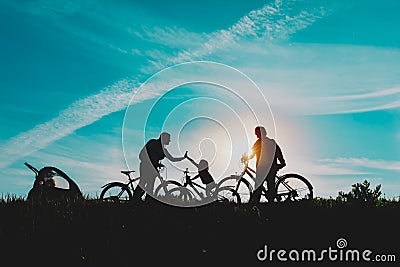 Happy mom, dad with kids biking at sunset nature Stock Photo