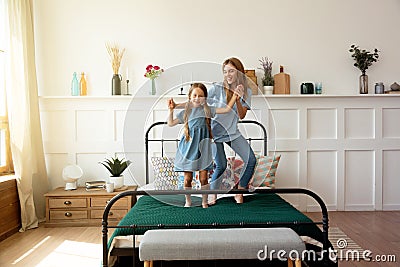 Mom and little daughter jumping and dancing at home Stock Photo