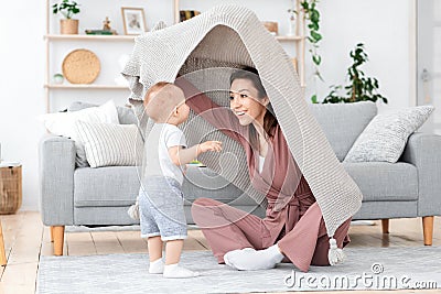 Happy Mom Playing With Toddler Son At Home, Peeking From Under Blanket Stock Photo
