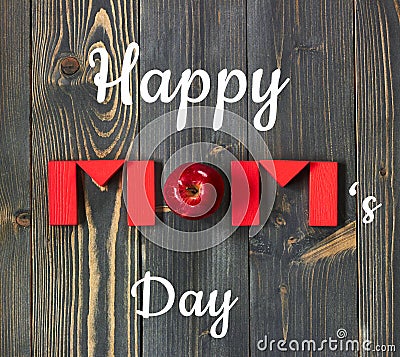 Happy mom`s day postcard on the background of Mom word from red toy bricks and an apple flat on dark textured wood Stock Photo