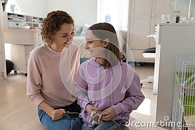 Happy mom and teen daughter play with domesticated mouse Stock Photo
