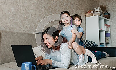 a happy mom tries to work and play with her kids at the same time. Stock Photo