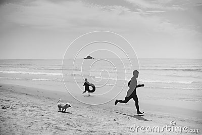 Happy moment of family with dog running on the beach Stock Photo