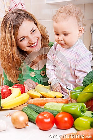 Happy mother with baby daughter preparing vegetables Stock Photo