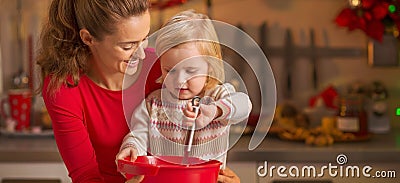 Happy mother and baby whisking dough in christmas kitchen Stock Photo