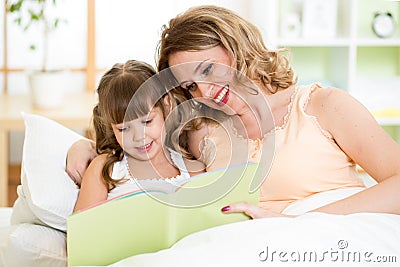 Happy mother and daughter reading a book together Stock Photo