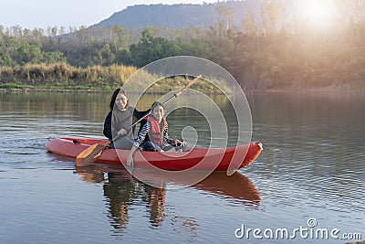 Mother and daughter rowing boat on calm waters Stock Photo