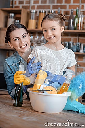 Happy mother and daughter in rubber gloves with cleaning supplies Stock Photo