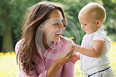 Happy mother giving flower to baby in the park Stock Photo