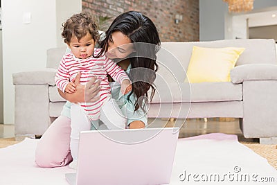 Happy mother with her baby using laptop Stock Photo