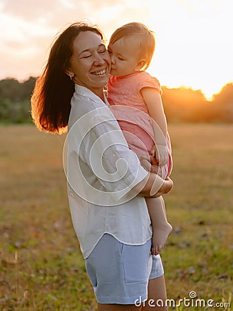 Happy mother with her baby outdoor with sunset tones in park Stock Photo