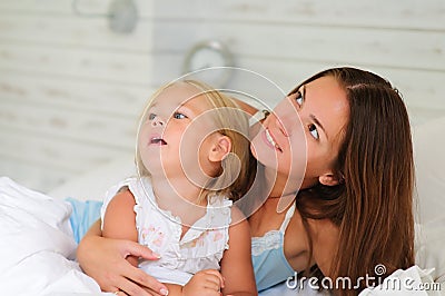 Happy mother and her little daughter lying in bed Stock Photo