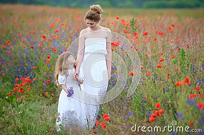 Happy mother with her little daughter in poppy field Stock Photo