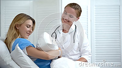 Happy mother holding newborn baby, smiling doctor looking at child, motherhood Stock Photo