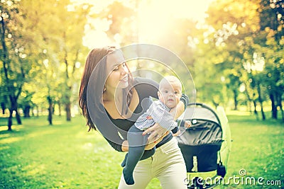 Happy mother holding and playing with newborn son. Happy woman holding infant, little kid and child Stock Photo