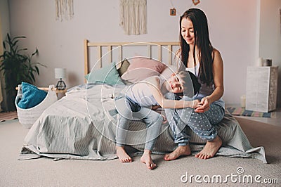 Happy mother hugs her toddler son in the morning, sitting on bed at home. Stock Photo