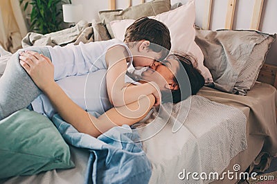 happy mother hugs her toddler son in the morning, sitting on bed at home. Stock Photo
