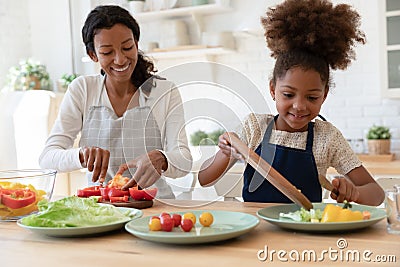 Happy mother and kid sharing cooking chores, preparing salad Stock Photo
