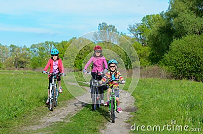 Happy mother and kids on bikes cycling outdoors Stock Photo