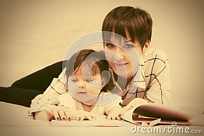 Happy mother and little baby girl reading a book on bed Stock Photo