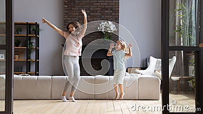 Happy mother with little daughter jumping in modern living room Stock Photo