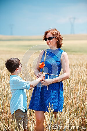 Happy mother with little son walking happily in wheat field Stock Photo