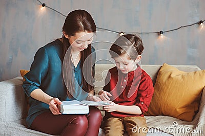Happy mother reading book to child son at home, learning toddlers to read, Stock Photo