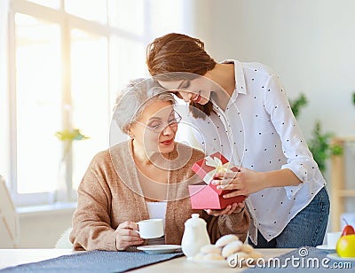 Happy mother`s day! adult daughter gives gift and congratulates an elderly mother on holiday Stock Photo