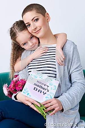 Happy Mother`s Day background. Cute little girl hugging mom after giving her mothers day card. Stock Photo