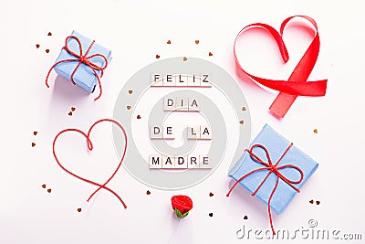 Happy Mother`s Day greeting card with red hearts, blue gift boxes and golden confetti on pastel table top, overhead shot. Feliz Stock Photo