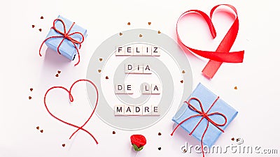 Happy Mother`s Day greeting card with red hearts, blue gift boxes and golden confetti on pastel table top, overhead shot. Feliz Stock Photo