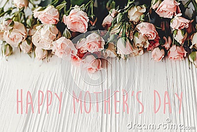 Happy Mother`s Day text sign at pink small roses on wooden background, space for text. Tender Flower border, Floral greeting card Stock Photo