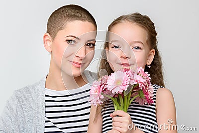 Happy Mother`s Day, Women`s day or Birthday background. Cute little girl giving mom, cancer survivor, bouquet of pink daisies. Stock Photo