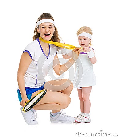 Happy mother showing baby medal for achievements in tennis Stock Photo
