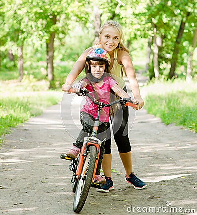 Happy mother teaches his daughter to ride a bike Stock Photo