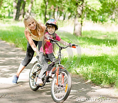 Happy mother teaches his daughter to ride a bike Stock Photo