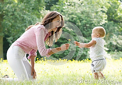 Happy mother teaching baby to walk in the park Stock Photo