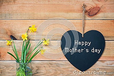 Happy mothers day card, wood planks with daffodils and a blackboard in shape of a heart Stock Photo