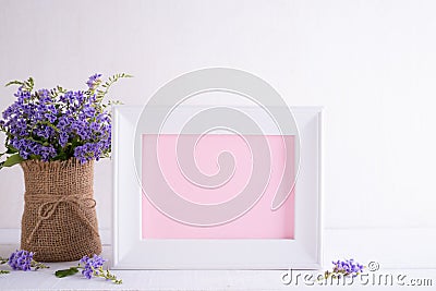 Happy mothers day concept. White picture frame with lovely purple flower in vase on white wooden table Stock Photo