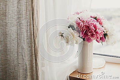 Happy Mothers day. Lovely peony bouquet in sunny light on rustic wooden window sill. Stylish pink and white peonies in vase on Stock Photo