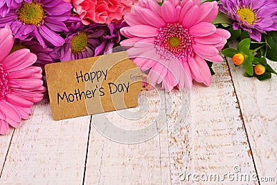 Happy Mothers Day tag close up with flowers over white wood Stock Photo