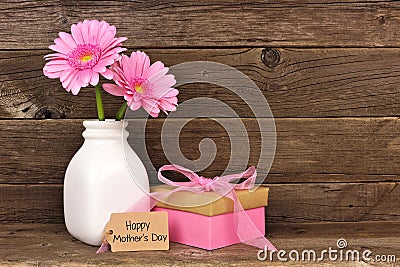 Happy Mothers Day tag with gift and pink flowers against rustic wood Stock Photo