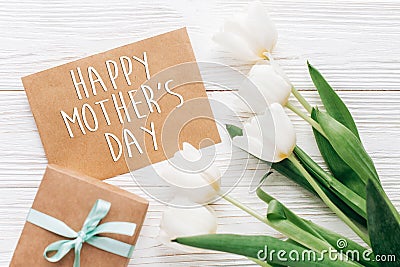 happy mothers day text sign on stylish craft present with greeting card and tulips on white wooden rustic background. flat lay wi Stock Photo