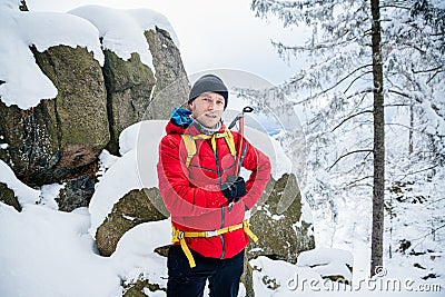 Happy mountaineer reaches the top of a mountain. He is holding an ice ax. Stock Photo