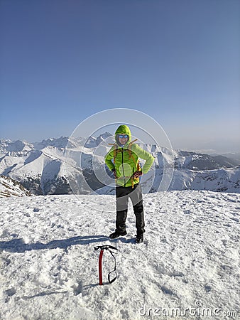 Happy mountaineer reaches the top of a snowy mountain in a sunny winter. Stock Photo