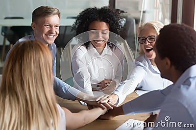 Happy multi ethnic employees stacking hands engaged in team building Stock Photo