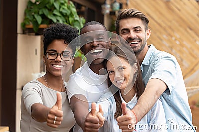 Happy multi-ethnic friends group showing thumbs up looking at camera Stock Photo